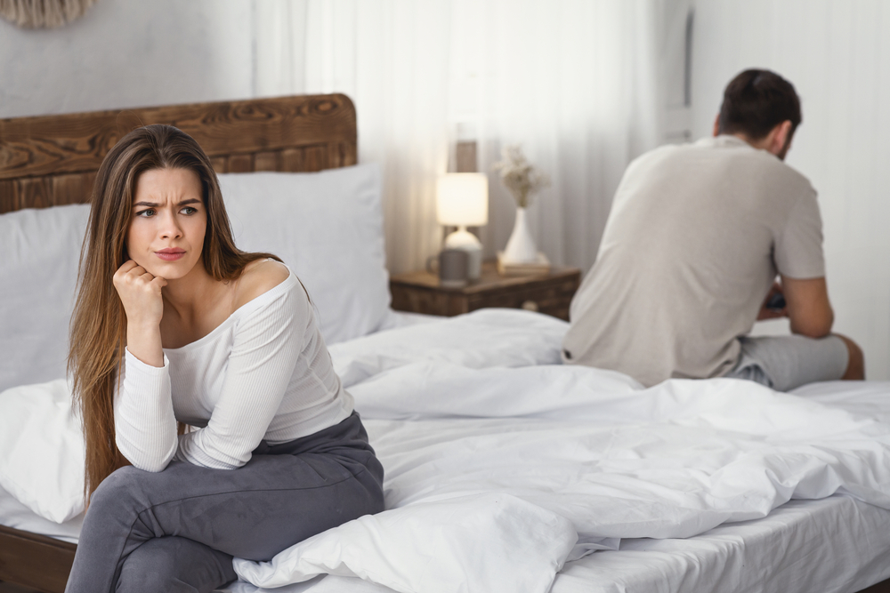 Angry couple sitting on opposite sides of bed