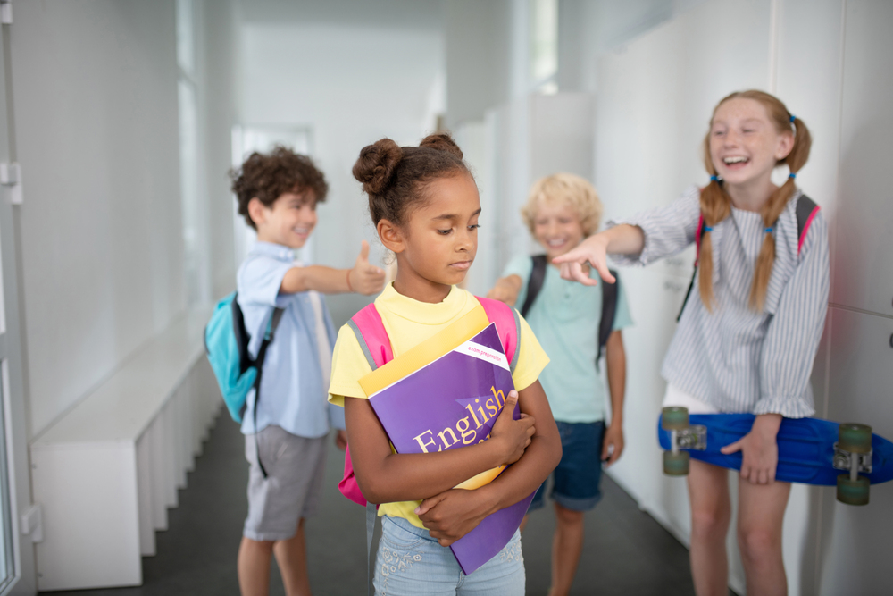 Students pointing and laughing at girl in hallway