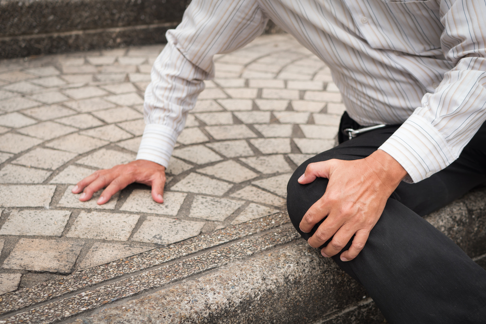 Man sitting on stairs holding knee after falling