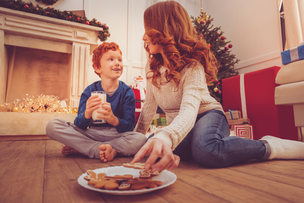 Mother and son in front of Christmas tree eating cookies