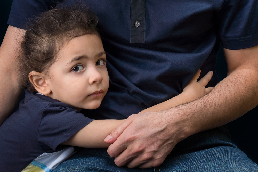 Child nervously hugging an adult.