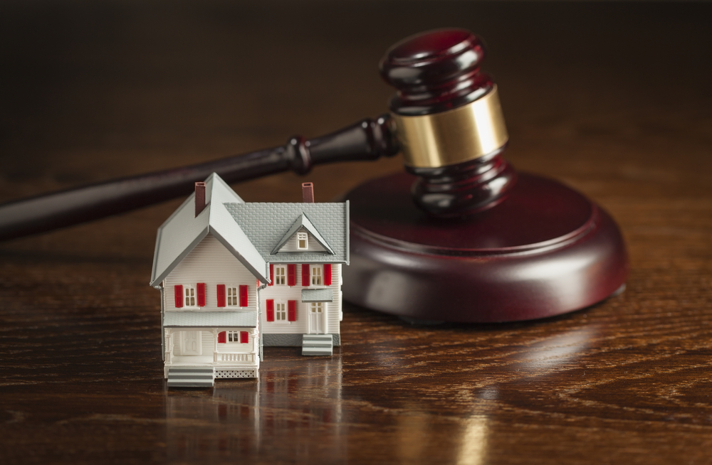 Small model house on table next to judge's gavel