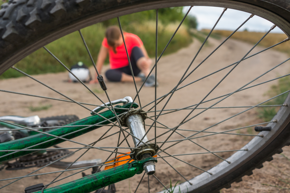 Injured woman seen through spokes of overturned bike