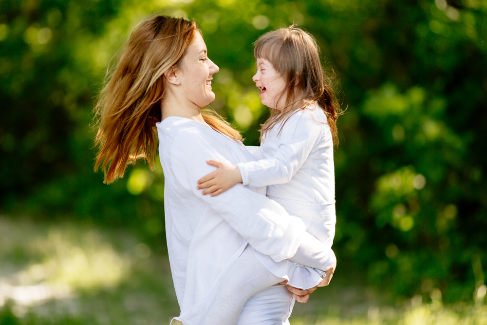 Mother holding daughter with Downs syndrome outdoors