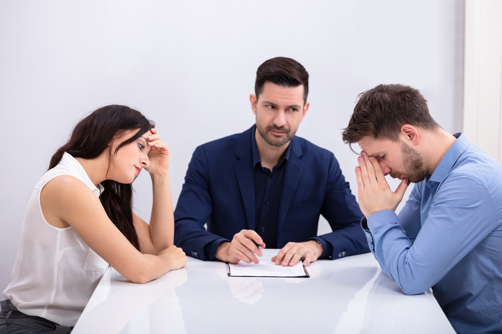 Mediator sitting between upset couple facing each other at a table