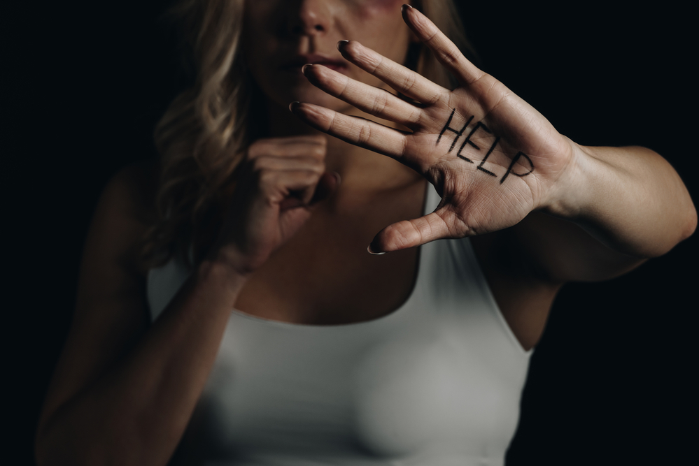 Woman in white tanktop holding out hand that says HELP