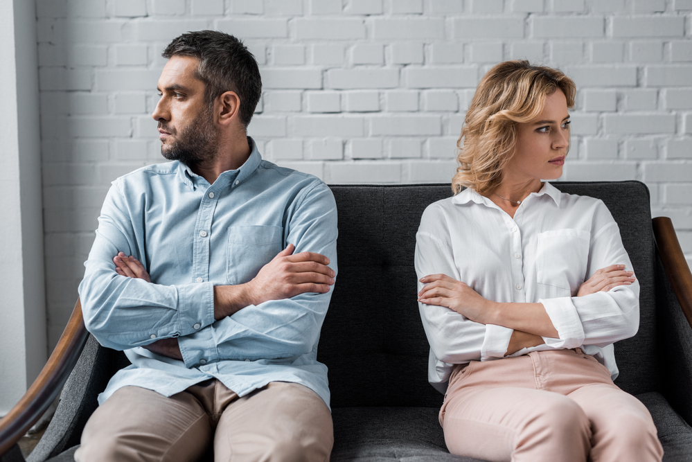 Angry couple sitting on couch and looking away from each other