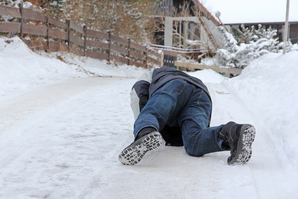 Man lying on snowy sidewalk after falling down