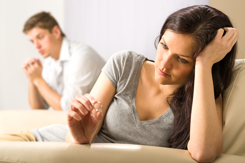 Woman on couch looking at wedding ring