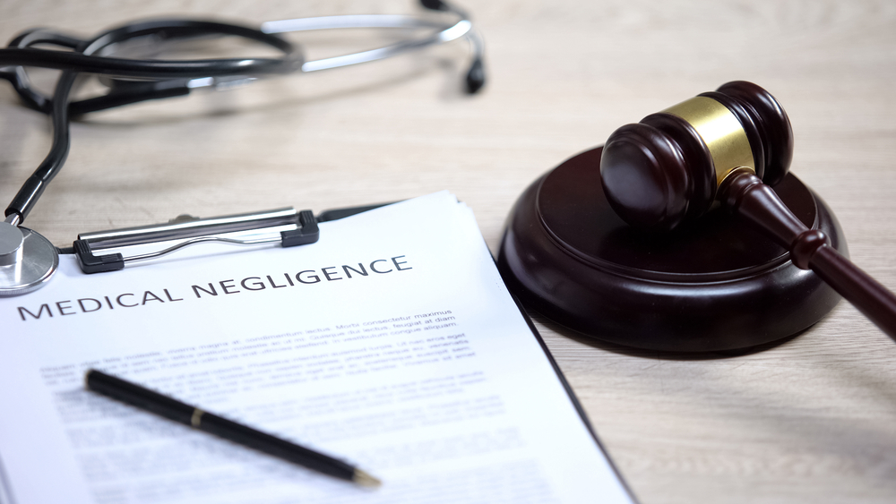 Gavel on table next to medical malpractice documents and stethoscope