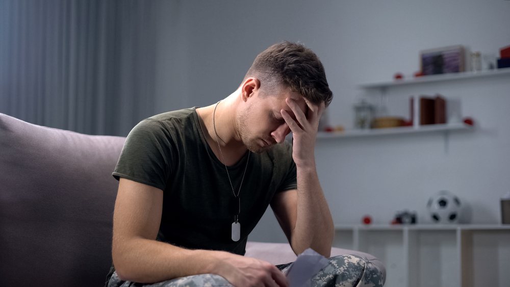 Upset soldier on couch holding photo