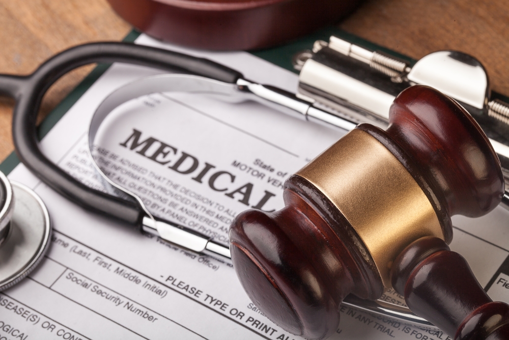Wooden gavel and stethoscope on medical paperwork