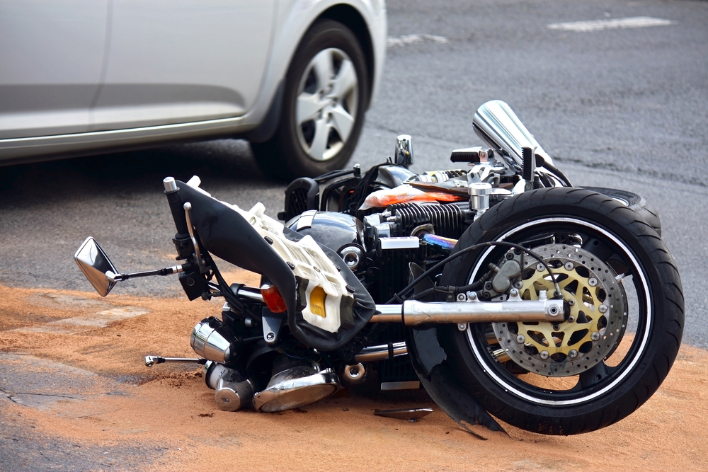 Motorcycle lying in street next to car