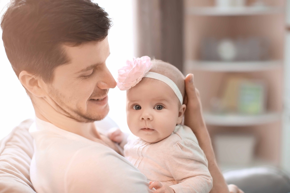 Young dad holding baby girl on couch