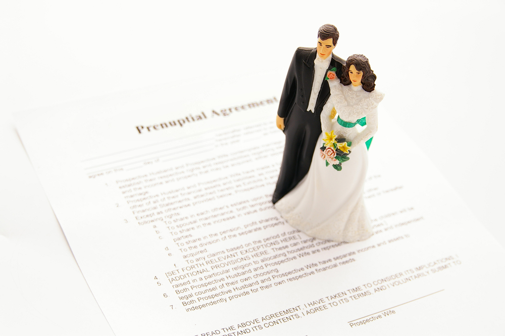 Wedding cake topper couple on top of prenuptial agreement