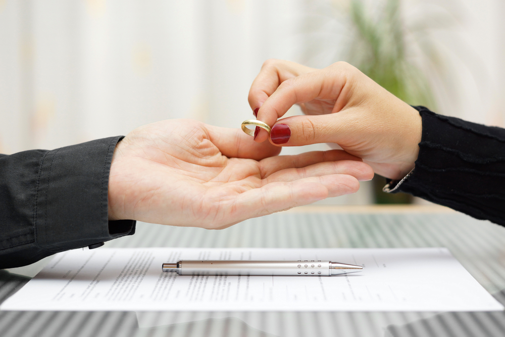 Woman's hand dropping ring into man's hand