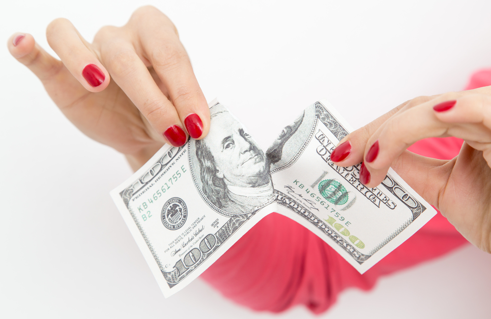 Woman tearing $100 bill in half