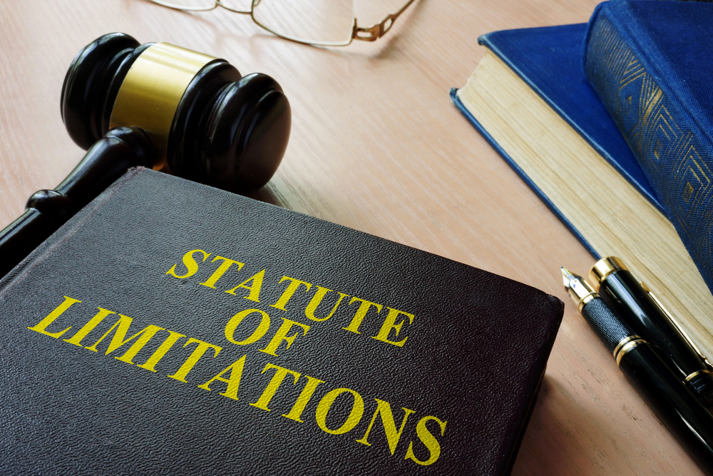 Statute of limitations law book on desk with gavel, glasses, books, and pen