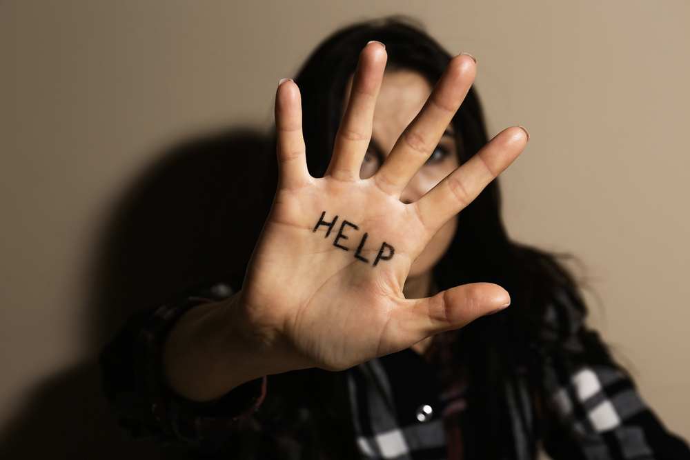 Woman holding up hand with "Help" written on palm