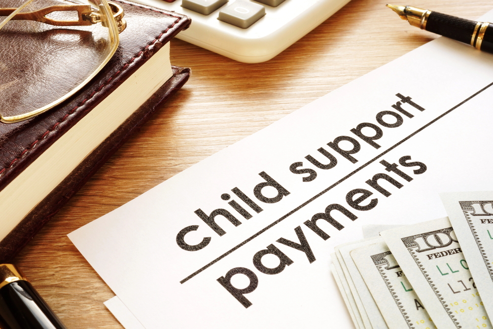 Child support payment paperwork on desk with fanned out money on top