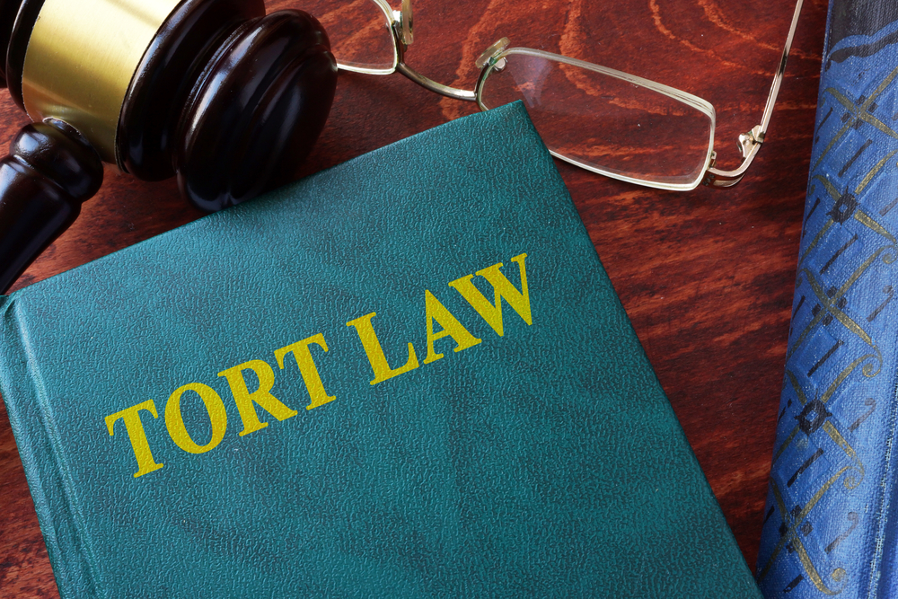 Tort law book on desk with gavel and glasses