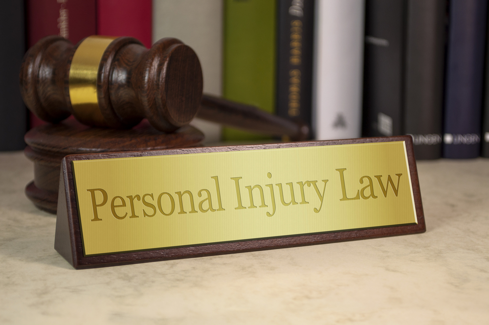 Personal injury law on gold plaque with judge's gavel behind it