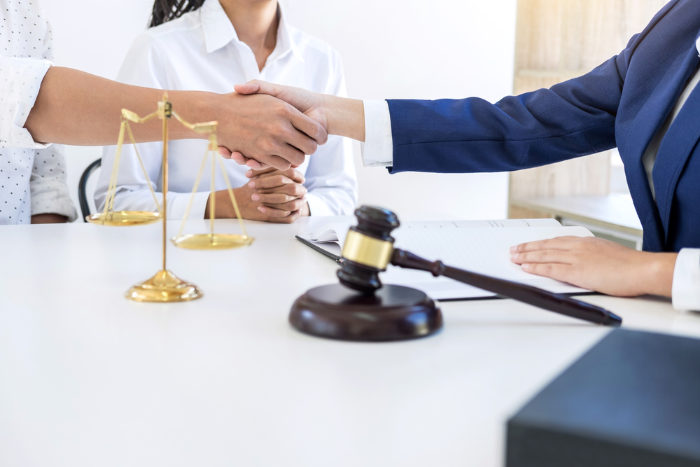 People shaking hands beside judge gavel at lawyer desk