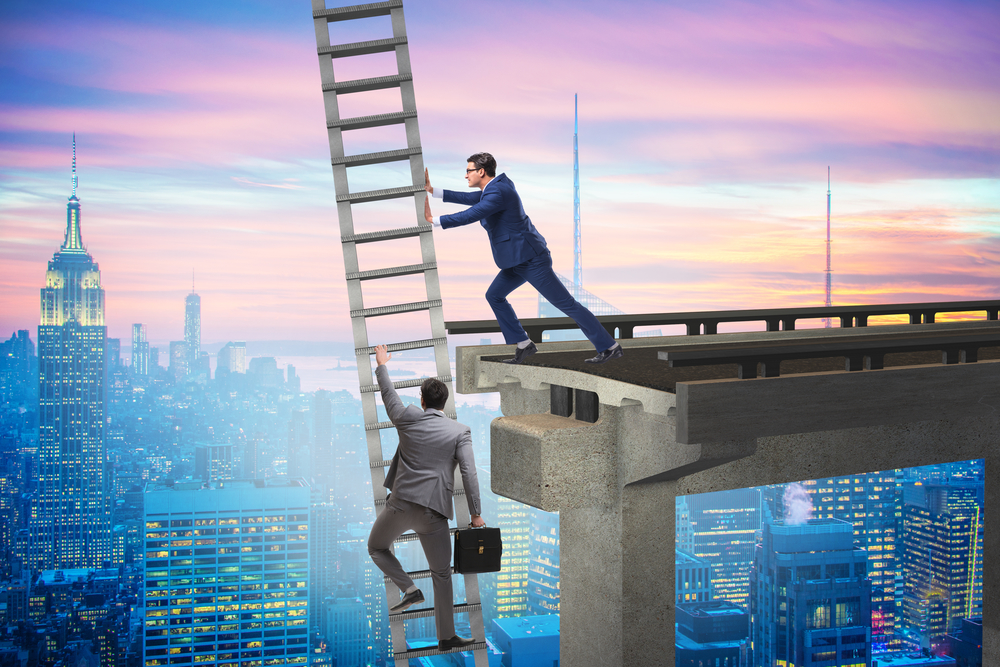 Businessman pushing over ladder while another tries to climb