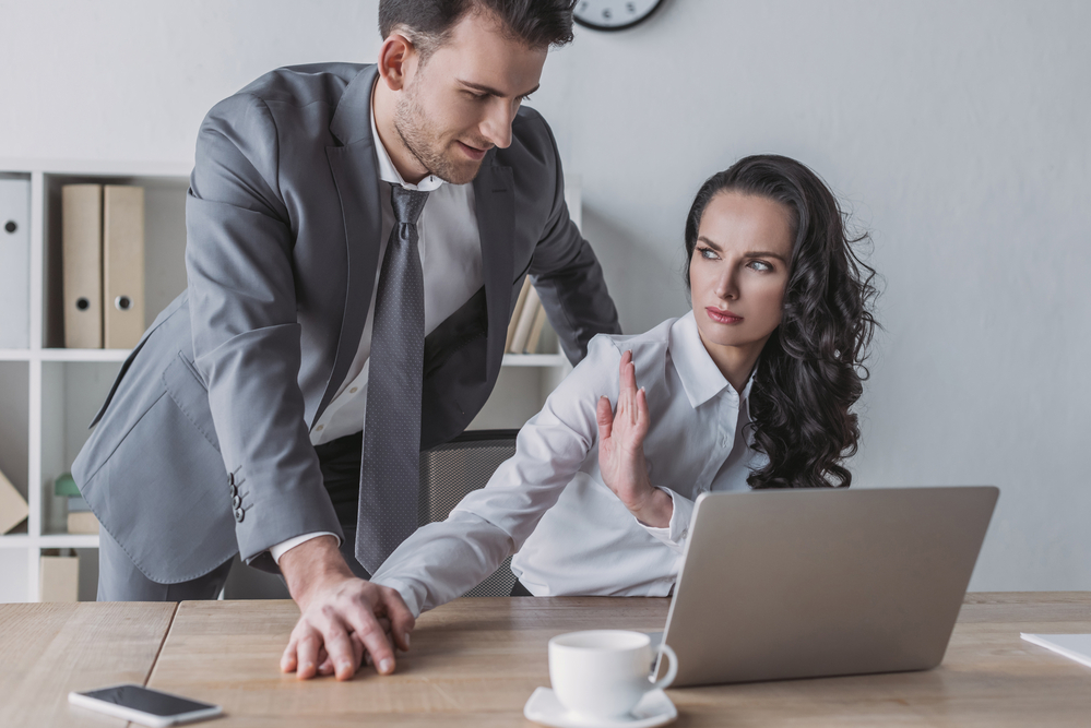 Woman pulling away from coworker touching her hand